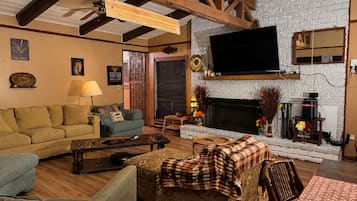 Un accogliente soggiorno con camino, travi in legno e una TV a schermo piatto.