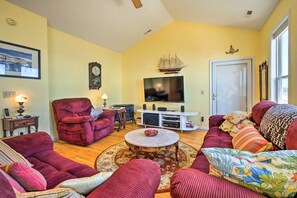 A living room with a red sofa set, a television, and a small ship decoration on the wall. - Waterfront Sneads Ferry Retreat w Deck & Bar! (Sneads Ferry)