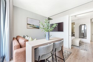 A modern living room with a sofa, a coffee table, and a TV mounted on the wall. - One Rosebank | Contemporary Comfort (Johannesburg)