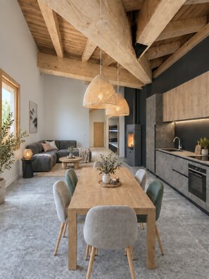A modern kitchen with a built-in stove, a dining area with a wooden table and chairs, and a cozy living space with a sofa and a fireplace. - Reflet Des Cimes Loan Lodge (Les Belleville)