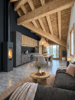 A modern loft with exposed wooden beams, a central dining area, a fireplace, and a cozy seating area. - Reflet Des Cimes Loan Lodge (Les Belleville)