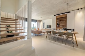 Interior moderno com escada, área de refeições e cozinha.