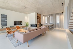 A modern living room with a sofa, chairs, a coffee table, a TV, and a dining area with a table and chairs. - Luxury 4-Bedroom Villa in Primošten with Private Pool & Panoramic Sea Views (Primošten)