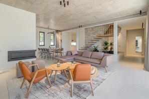 Uma sala de estar moderna com sofá, cadeiras, mesa de centro e lareira.