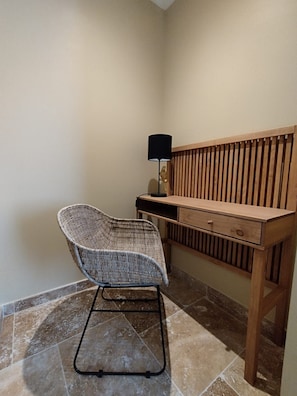 A corner room with a wooden desk, a wicker chair, and a lamp. - Gîte romantique 4* au calme avec jacuzzi et vue sur le piémont cévenol (Lézan)