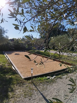An outdoor area with a dirt surface, surrounded by greenery and trees. - Gîte romantique 4* au calme avec jacuzzi et vue sur le piémont cévenol (Lézan)