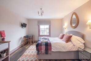 A bedroom with a bed, bedside table, lamp, wall-mounted TV, and a window with a view. - Wonderous Kensington Studio (London)