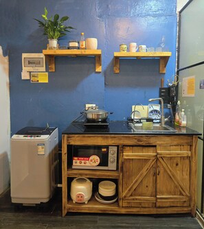 A compact kitchen with a refrigerator, a stove, a sink, and wooden shelves above holding various kitchen items. - OH Trendy homes Hoan Kiem LPH  - city center - 2 beds (Hoan Kiem)