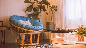 A room with a blue cushioned chair, a large potted plant, a table with a teapot, and a vase with flowers. - OH Trendy homes Hoan Kiem LPH  - city center - 2 beds (Hoan Kiem)