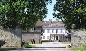 A large, historic building with a prominent entrance, a stone wall on one side, and a sign indicating the name 'Gutshef'. - New Listing (Nieheim)