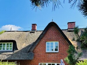 A traditional house with a thatched roof and brick walls, featuring a central window and chimney. - Holiday Home in Nieblum With Swimming Pool (Nieblum)