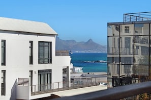 A modern building with a balcony overlooking a coastal view, including a mountain and the sea. - Fabulous 2-bedroom apartment in Eden on the Bay near top attractions (Cape Town)