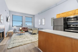 A modern kitchen with a stainless steel refrigerator, oven, and microwave. There is a wooden countertop and a dining area with a table and chairs. - Urban Oasis | Steps to Playhouse Square (Cleveland)