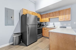 A modern kitchen with stainless steel appliances, wooden cabinets, and a white countertop. - Urban Oasis | Steps to Playhouse Square (Cleveland)