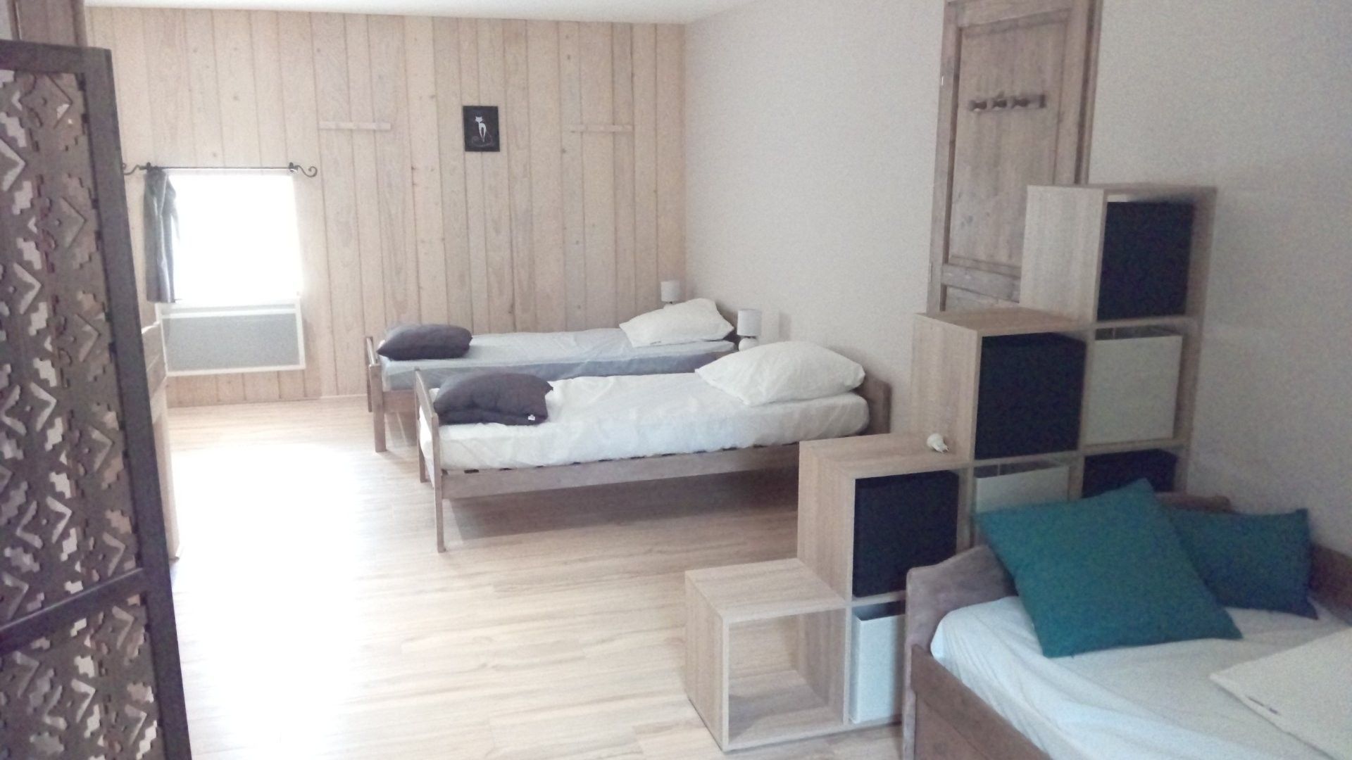 A room with two beds, a wooden floor, and a window.
