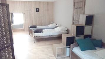 A room with two beds, a wooden floor, and a window.
