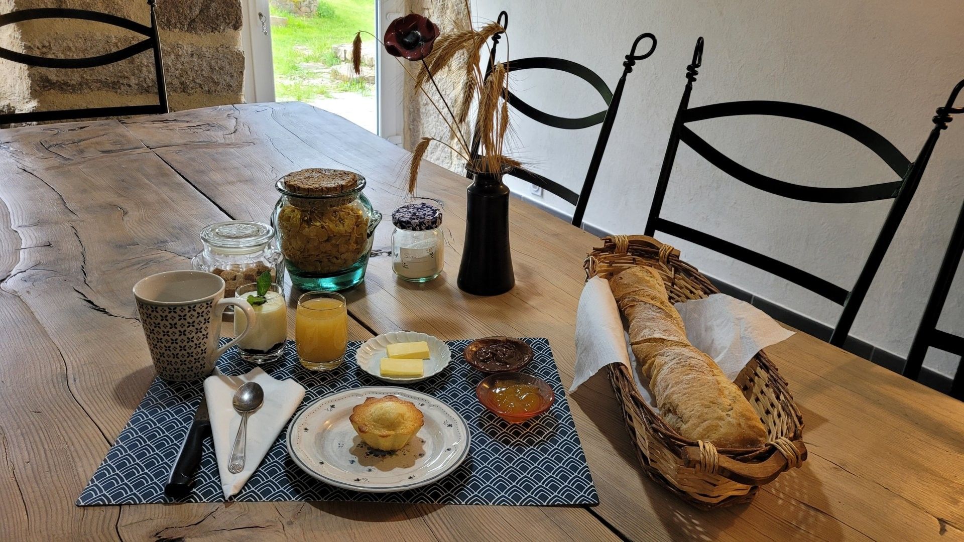 A wooden table with breakfast items including bread, butter, jam, and a muffin.