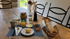 A wooden table with breakfast items including bread, butter, jam, and a muffin.