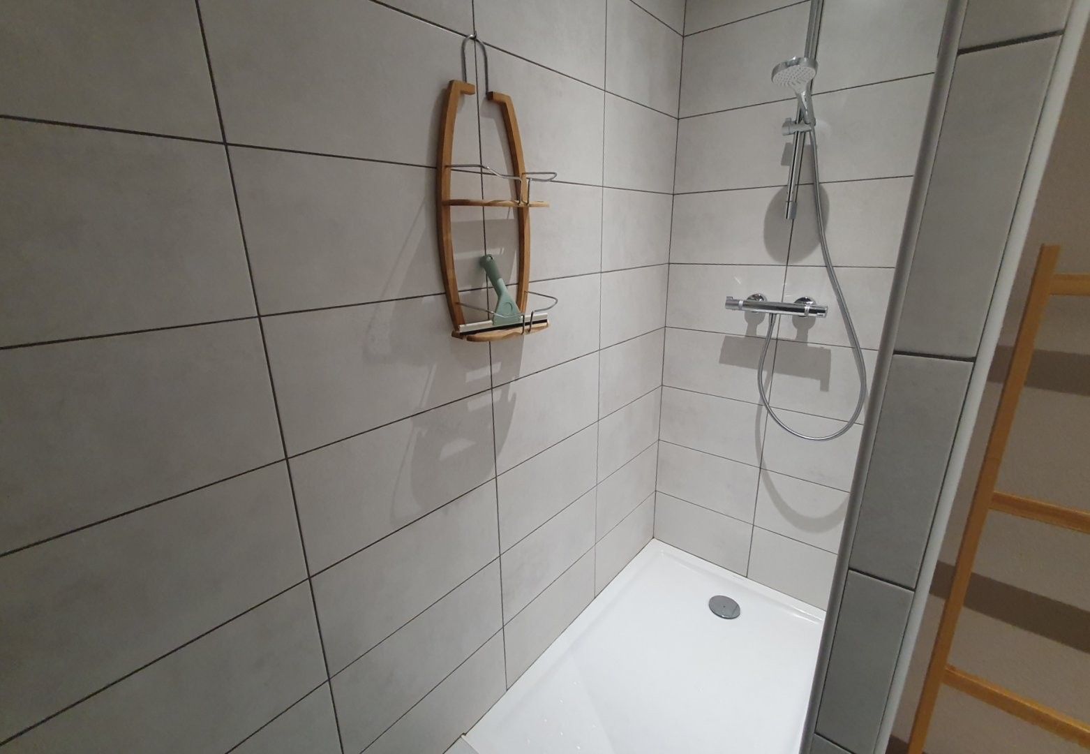 A small, tiled shower area with a showerhead and a handheld shower attachment.