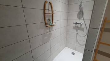A small, tiled shower area with a showerhead and a handheld shower attachment.