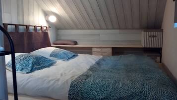 Ein Schlafzimmer mit einem Bett, Kissen, einer Bank und einem kleinen Tisch.