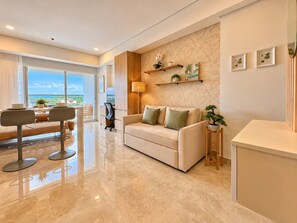 A modern living room with a sofa, a coffee table, and a dining area with chairs. - Suite Familiar Vista Piscina CB536 (Cartagena de Indias)