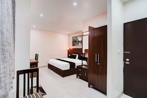 A bedroom with a bed, a wardrobe, a desk, and a chair.