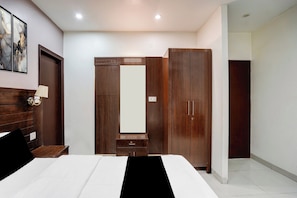 A bedroom with a bed, a nightstand, a wardrobe, and a mirror.