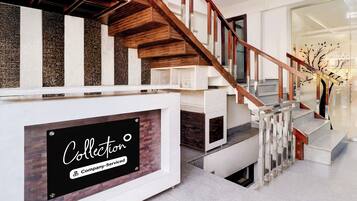 A modern staircase with a wooden handrail and white steps, leading to a landing with a sign that reads 'Collector Company-Service.'