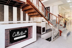 A modern staircase with a wooden handrail and white steps, leading to a landing with a sign that reads 'Collector Company-Service.'