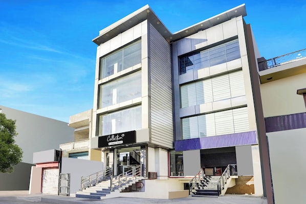 A modern building with a glass facade, a visible staircase, and a sign that reads 'Collection Company-Serviced'.