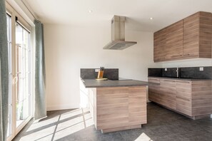 A modern kitchen with wooden cabinetry, a central island, and a large window. - New Listing (Cadzand)