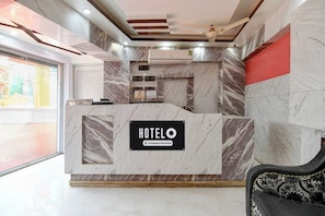 Un mostrador de recepción de hotel con detalles de mármol, un cartel con la hora de salida y una etiqueta de servicio de la empresa.