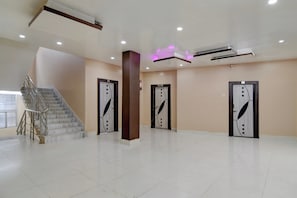 A spacious lobby with a marble staircase, three doors with decorative handles, and a modern ceiling with recessed lighting. - Hotel O Tarapith Temple (Tarapith)
