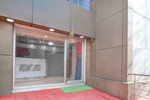 A building entrance with a glass door, a security camera, and a red and green mat outside. - Hotel O Tarapith Temple (Tarapith)
