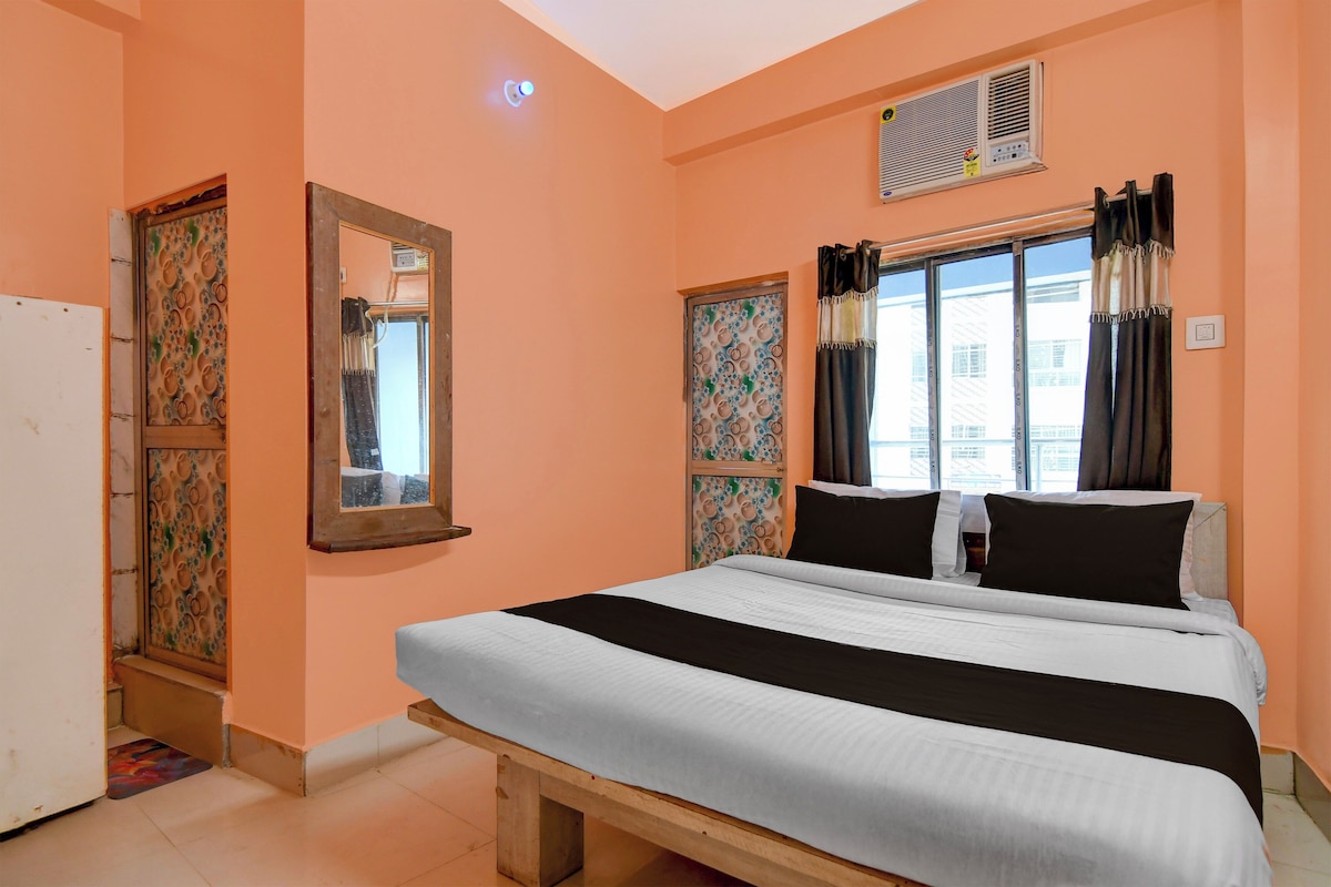 A bedroom with a bed, a window with curtains, a mirror, and a wall-mounted air conditioning unit.