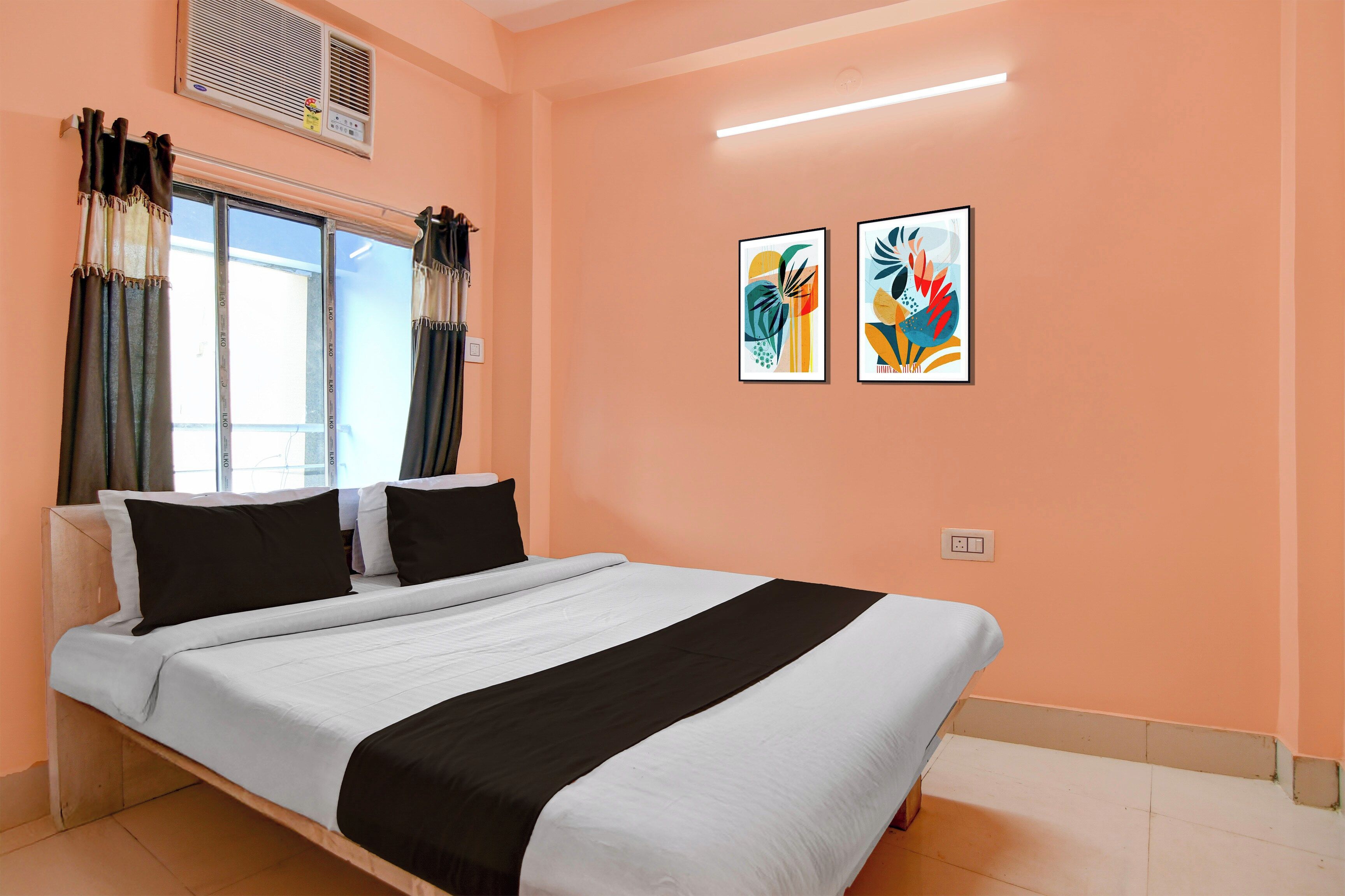 Una habitación de hotel con cama, cortinas, ventana, decoración en la pared y una lámpara en el techo.