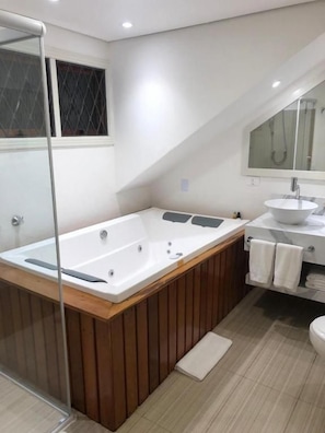 A modern bathroom with a freestanding bathtub, a glass shower enclosure, and a vanity with a sink and mirror. - POUSADA DAS LAVANDAS (Campos do Jordão)