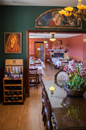 A restaurant interior with wooden tables, chairs, a wine rack, and a chandelier. - POUSADA DAS LAVANDAS (Campos do Jordão)