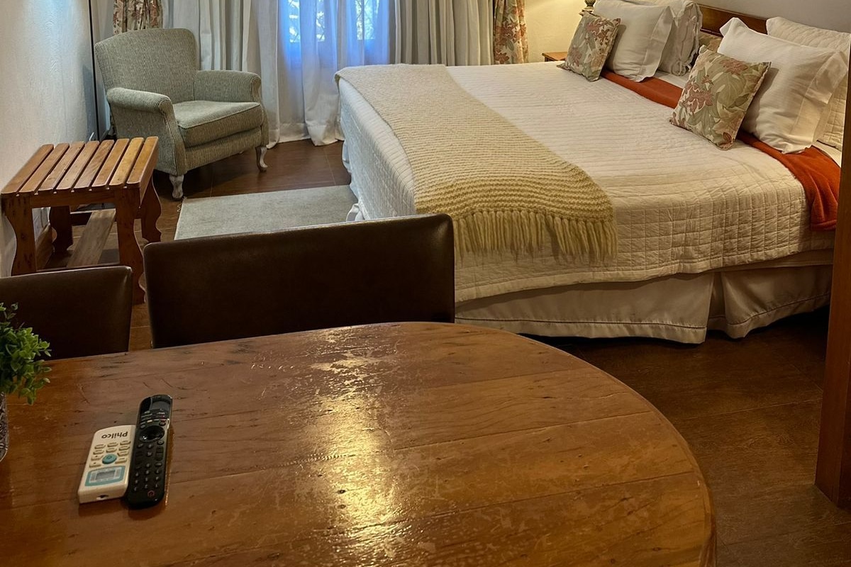A hotel room with a bed, a chair, a table, and a lamp.