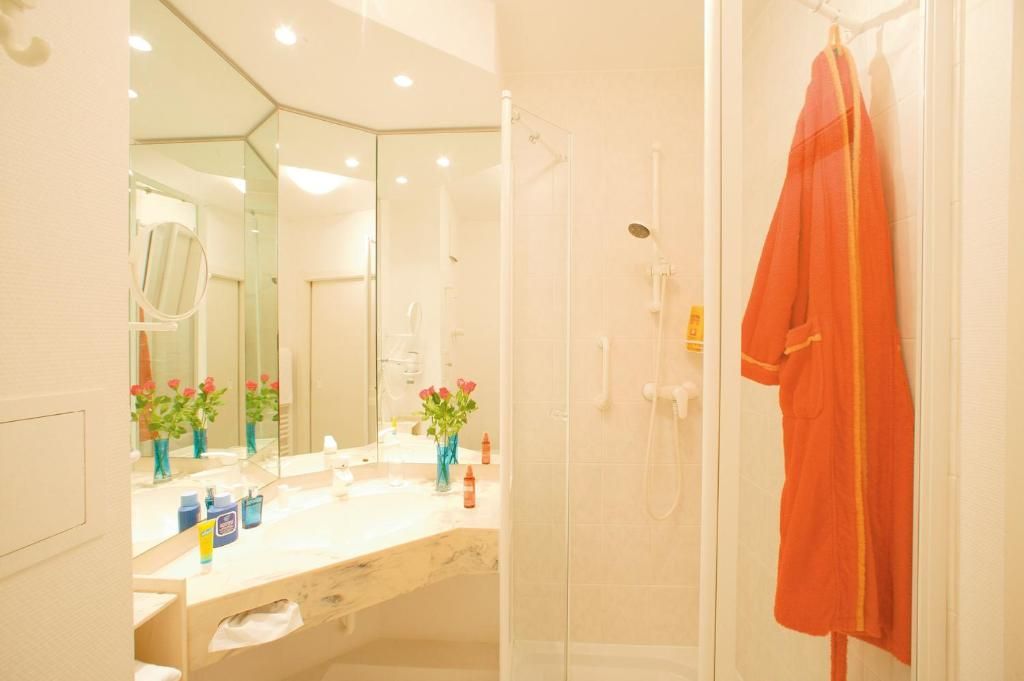 Ein Badezimmer mit einer Glasdusche, einem weißen Waschbecken mit Spiegel und einem Handtuchhalter mit Handtuch.