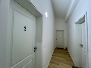 A hallway with white doors numbered 2 and 3, wooden flooring, and a white wall.