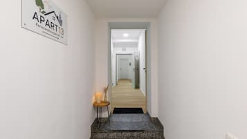 A hallway leading to a door labeled 'APART 13' with a sign indicating 'Wohnungen Nr. 2-4'.