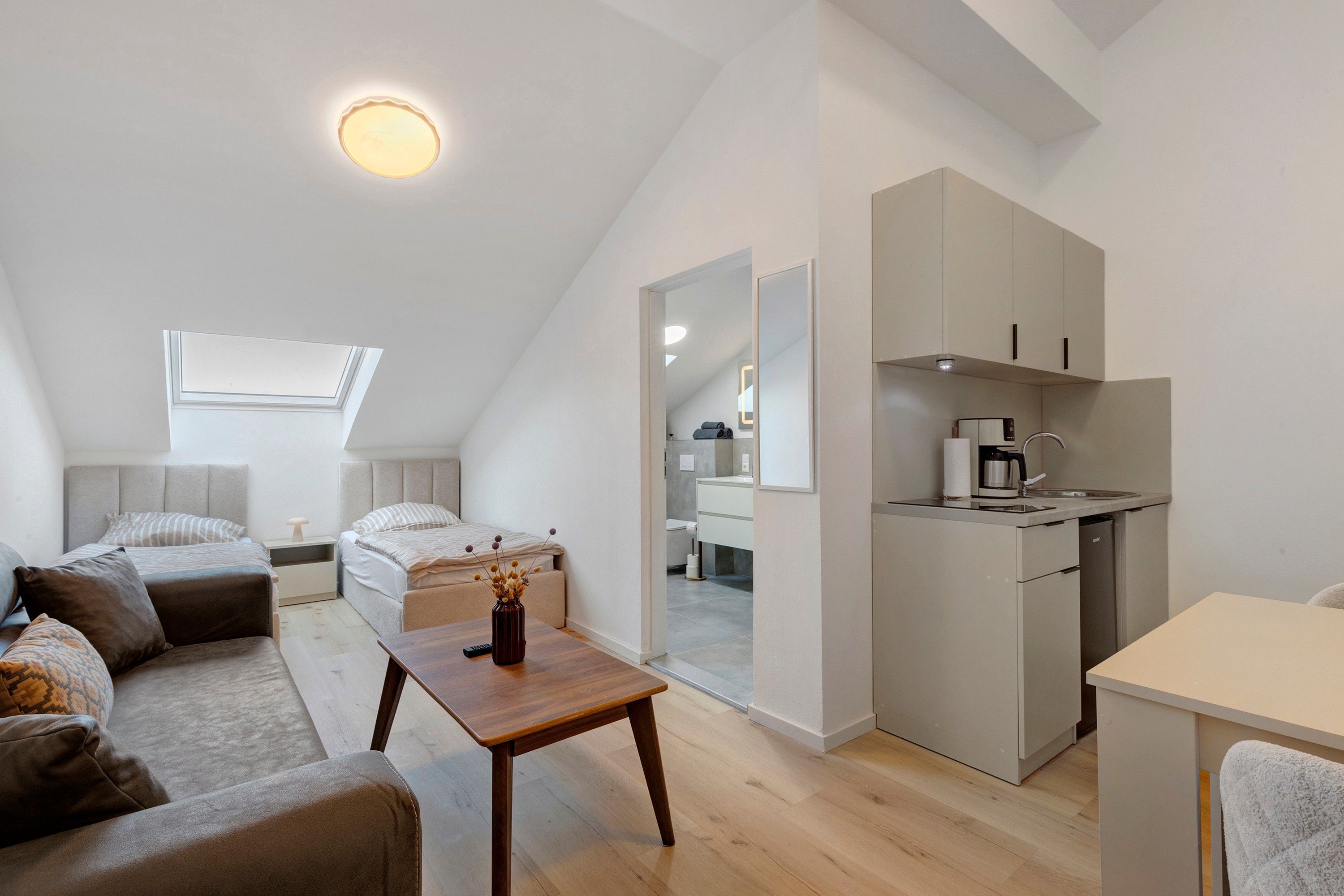 Eine moderne Lofts-Wohnung mit Küche, Essbereich und einem Schlafzimmer mit großem Fenster.