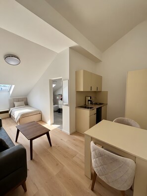 Un espace de vie compact comprenant une chambre en mezzanine, une kitchenette et un coin repas.