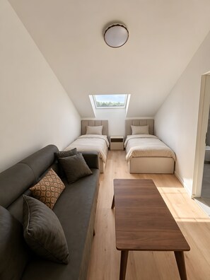 A compact, modern room with a loft bed, a sofa, and a wooden table.