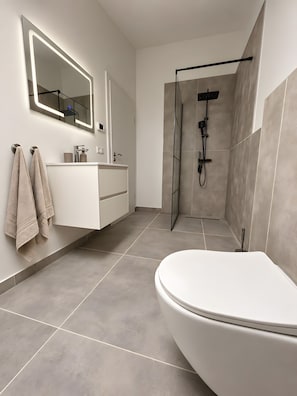 Une salle de bain moderne avec une baignoire sur pieds, un meuble-lavabo avec miroir et un espace douche.
