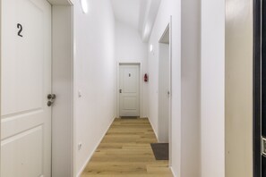 A narrow hallway with wooden flooring, white walls, and doors numbered 2 and 3.