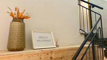 A wooden bench with a framed welcome sign and a decorative vase with dried flowers.