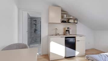 A compact kitchenette with a coffee maker, a dishwasher, and a small countertop.